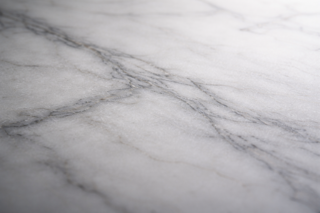carrara_marble_surface_soft_gray_white_veining_matte_natural_light_quiet_luxury_material_texture