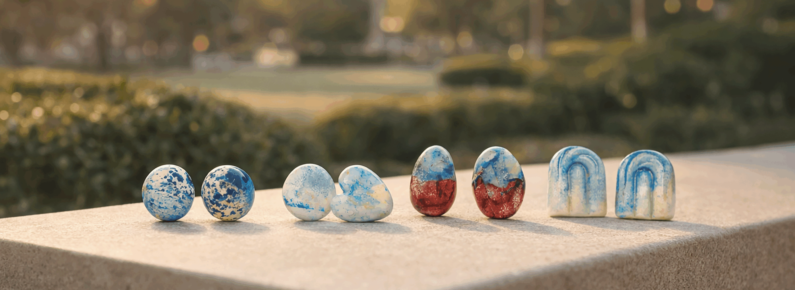 urban_aura_ceramic_hand_painted_earrings_collection_on_architectural_stone_bench_in_warm_city_park_luxury_campaign_medium_format_photography