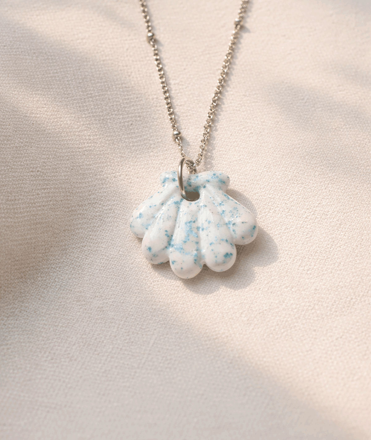 handmade_ceramic_shell_pendant_white_blue_speckled_glossy_camino_inspired_necklace
