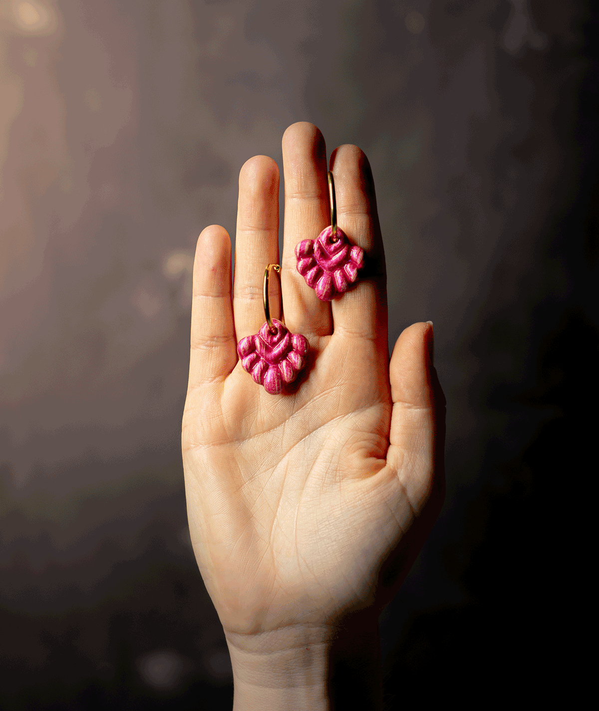 charm_05_a coral pink hoop earrings with glossy fuchsia polymer clay charms and gold-tone hoops displayed on a hand