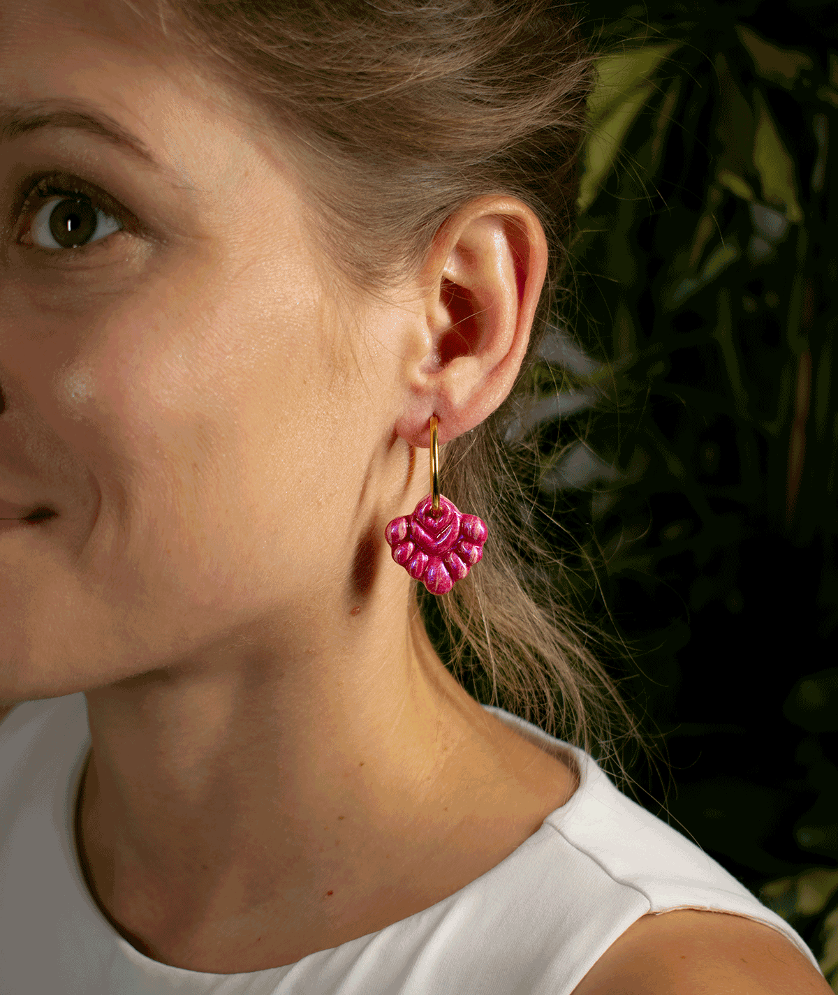charm_05_b woman wearing coral pink hoop earrings with bright pink textured charms and gold-tone hoops