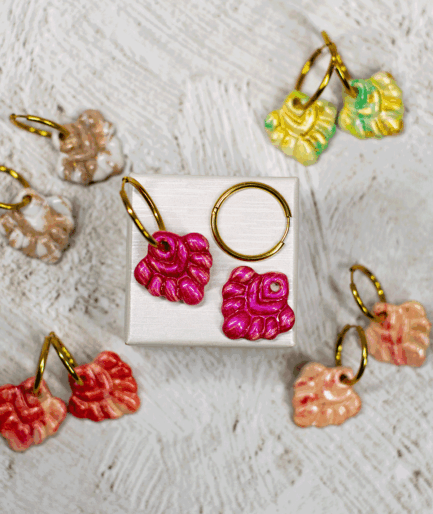 coral pink hoop earrings displayed with other handmade polymer clay earrings in green, peach, beige and red