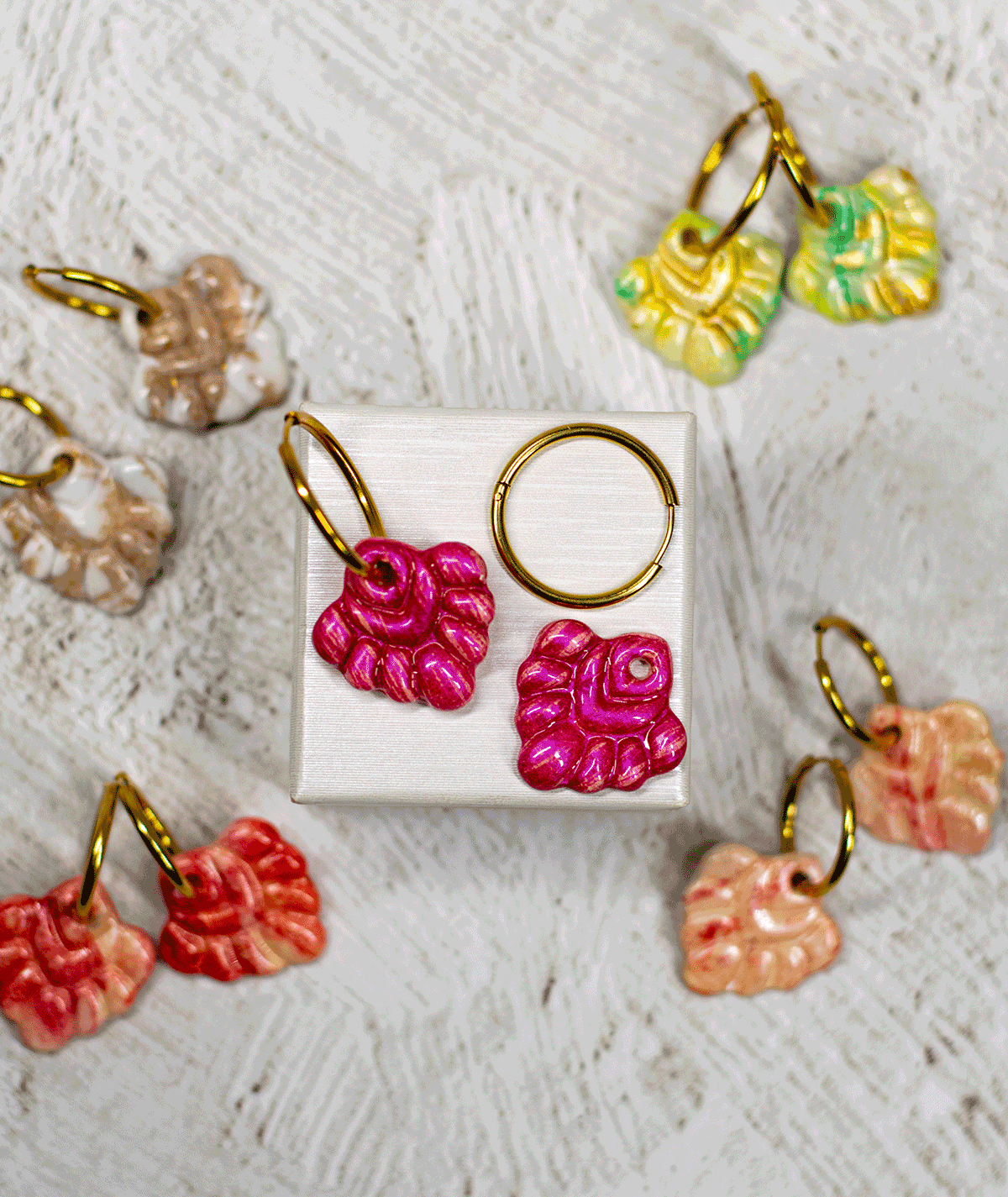 charm_05_c2 coral pink hoop earrings displayed with other handmade polymer clay earrings in green, peach, beige and red