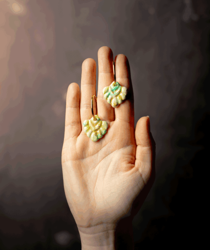 mint coral hoop earrings with green and gold polymer clay charms displayed on an open hand