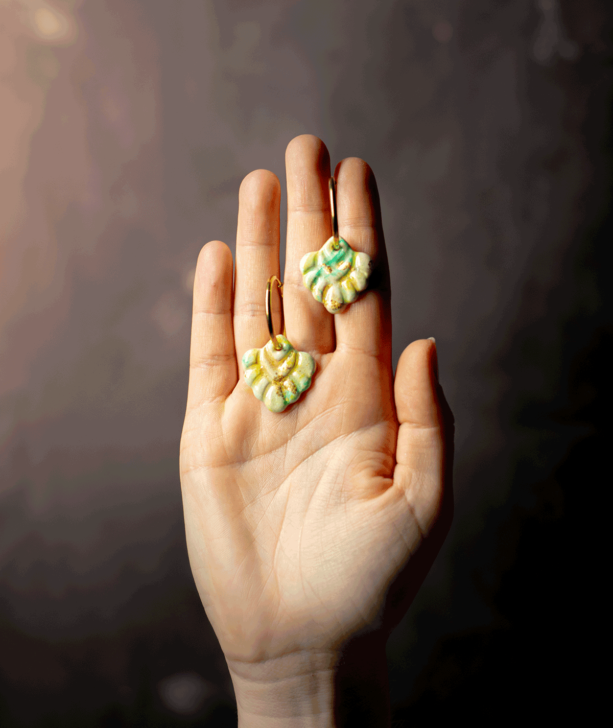 charm_06_a mint coral hoop earrings with green and gold polymer clay charms displayed on an open hand