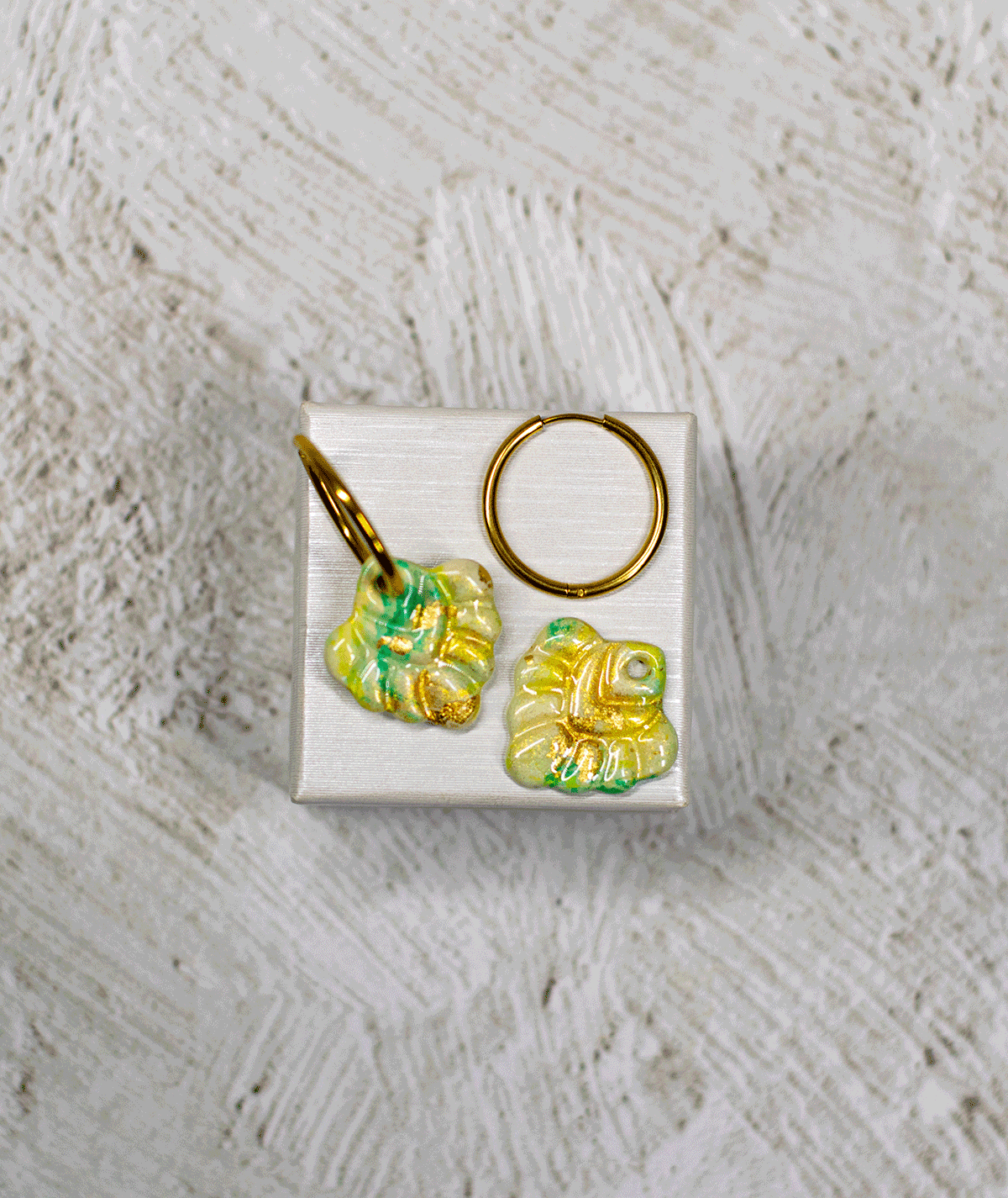 charm_06_c1 mint coral hoop earrings with glossy polymer clay charms in green, yellow and gold on a white display stand
