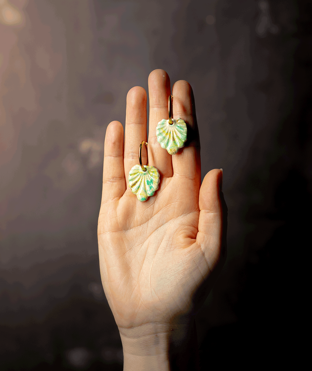 charm_08_a Mint Green Shell Earrings with gold-tone hoops and handcrafted polymer clay charms displayed on a hand
