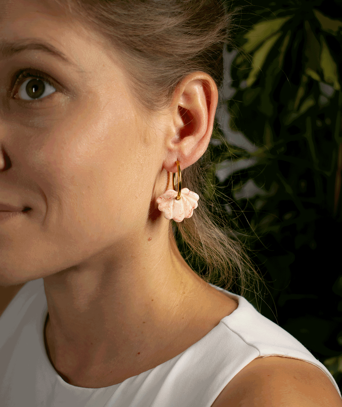 charm_10_b woman wearing peach shell hoop earrings with sculpted blush pink polymer clay charms and gold-tone hoops
