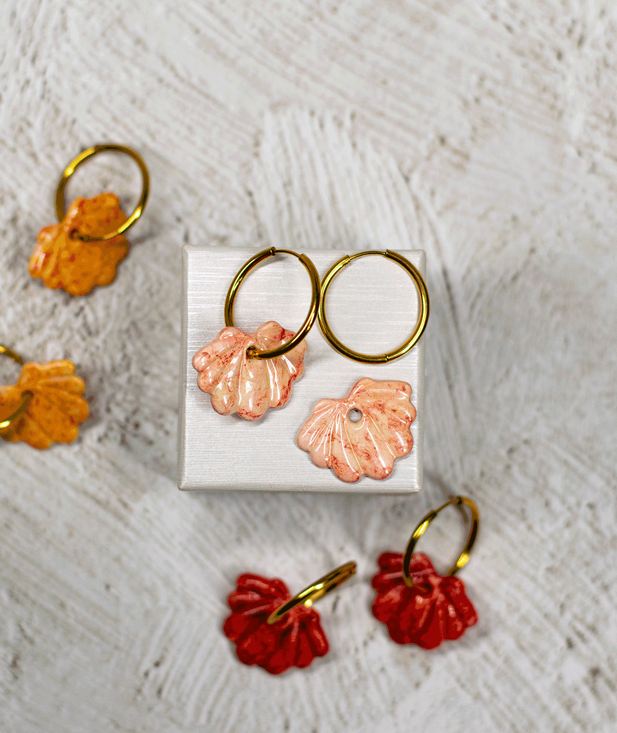 charm_10_c2 peach shell hoop earrings displayed with other handmade shell earrings in orange and red