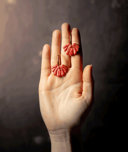 red shell hoop earrings with glossy ruby red polymer clay charms and gold-tone hoops displayed on an open hand