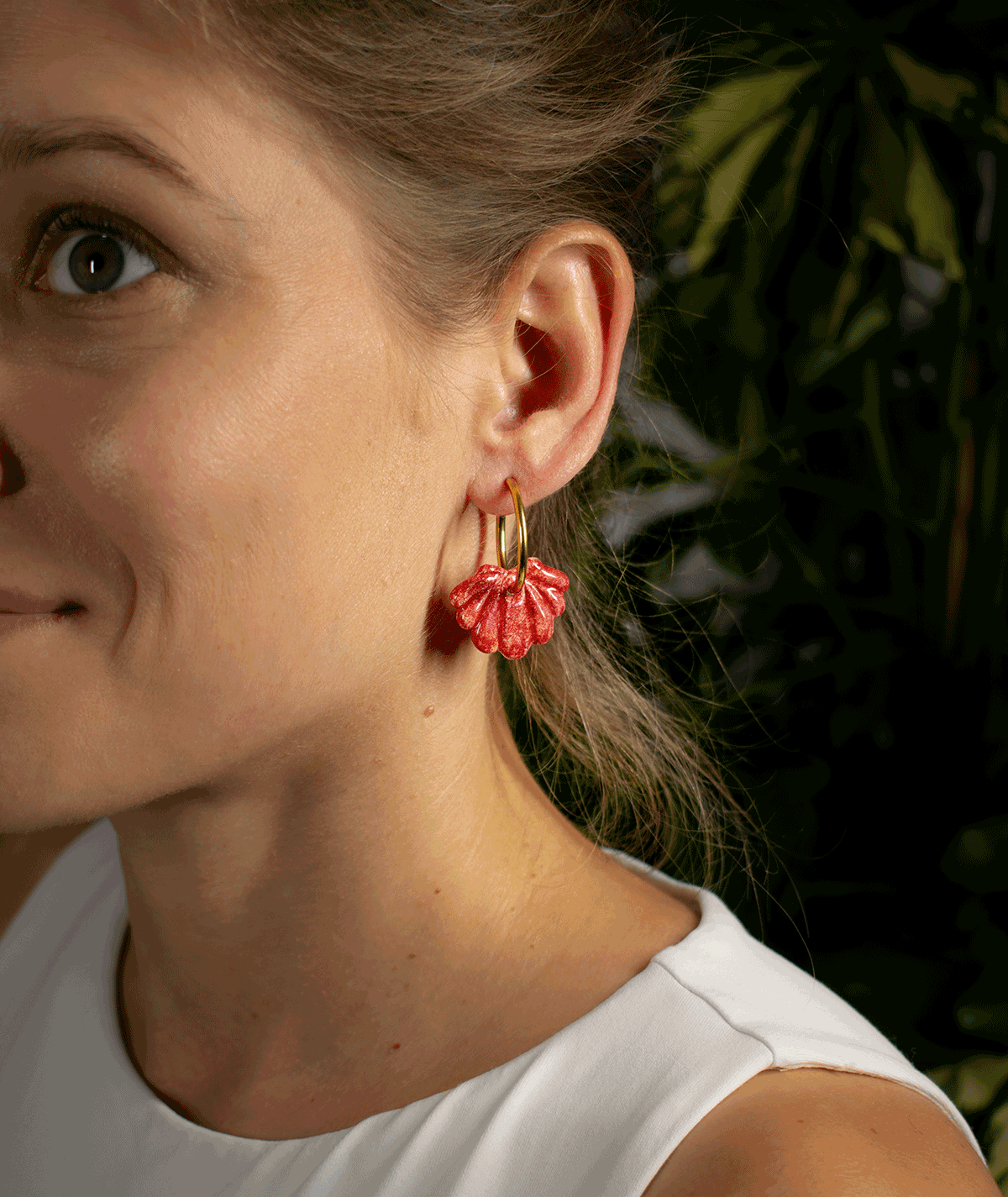 charm_11_b woman wearing red shell hoop earrings with textured ruby red seashell charms and gold-tone hoops