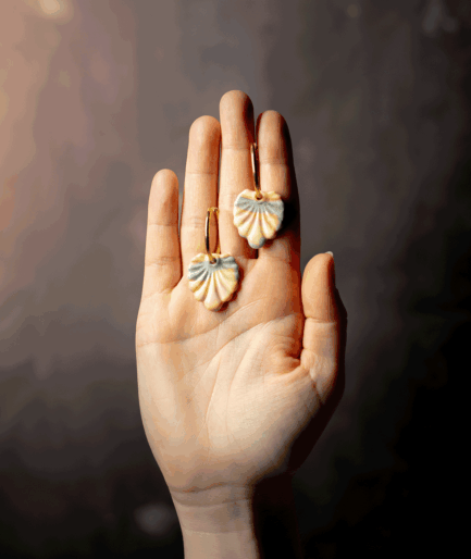 Pastel Shell Earrings with peach, yellow and grey-blue polymer clay charms on gold-tone hoops displayed on a hand