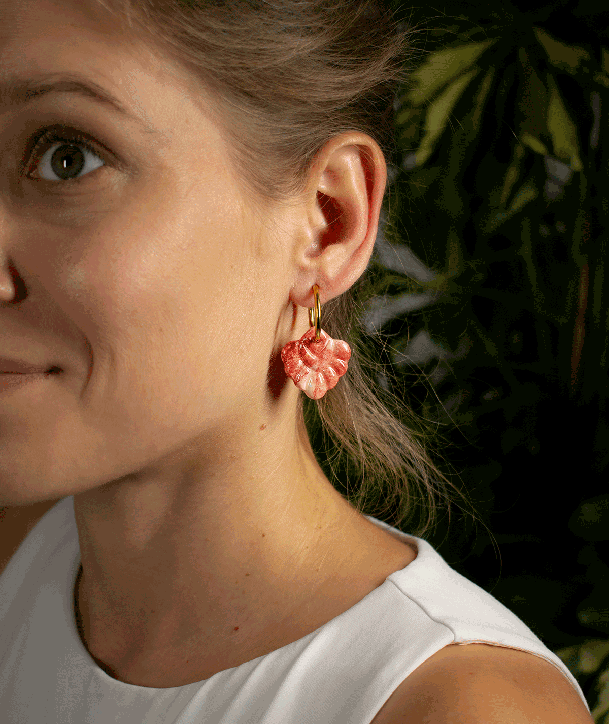 charm_14_b woman wearing coral red hoop earrings with sculpted pink and red polymer clay charms and gold-tone hoops
