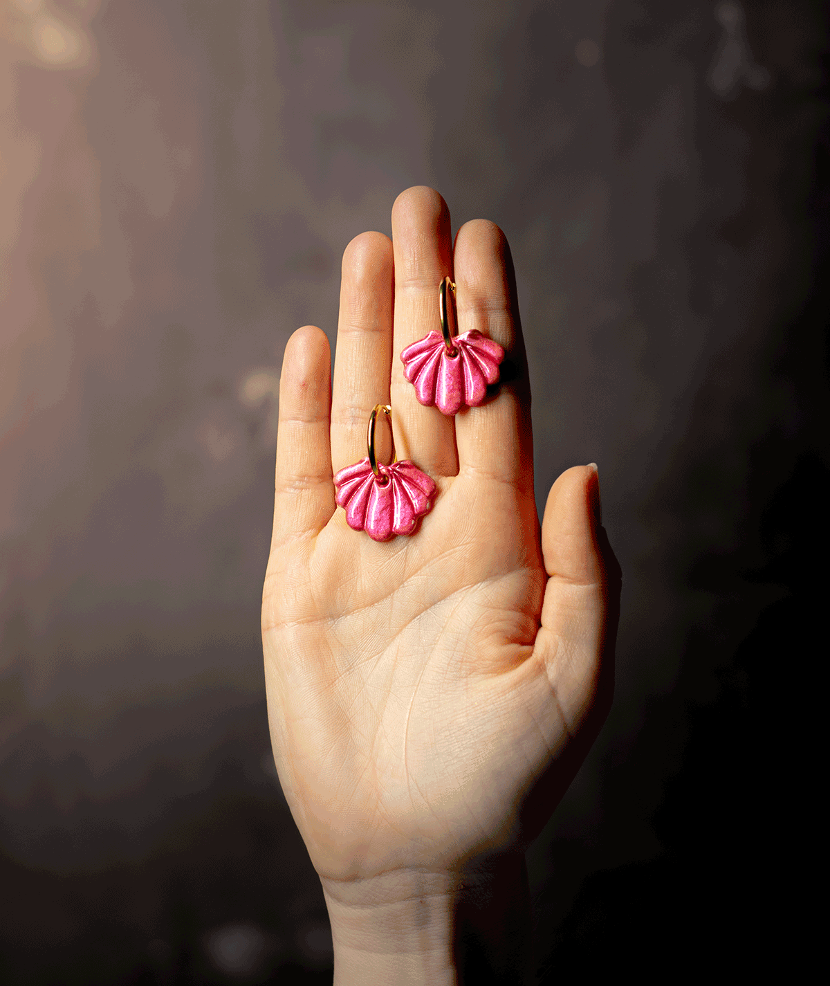 charm_15_a raspberry shell hoop earrings with glossy pink polymer clay charms and gold-tone hoops displayed on an open hand