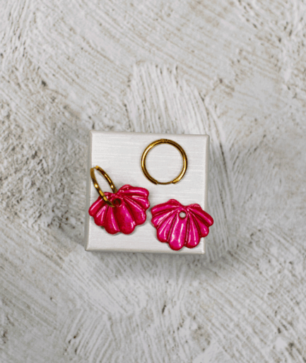 raspberry shell hoop earrings with metallic pink polymer clay charms and raised ridges on a white display stand