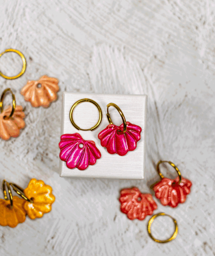 raspberry shell hoop earrings displayed with handmade polymer clay seashell earrings in peach, orange and coral red