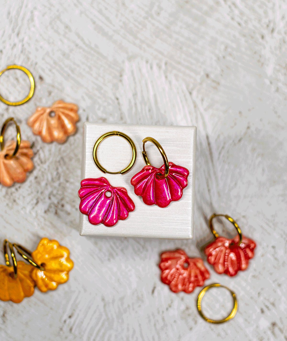 charm_15_c2 raspberry shell hoop earrings displayed with handmade polymer clay seashell earrings in peach, orange and coral red