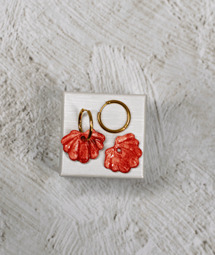 terracotta shell hoop earrings with glossy speckled red polymer clay charms and sculpted ridges on a white display stand