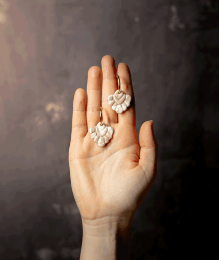 beige coral hoop earrings with ivory white and sandy beige polymer clay charms displayed on an open hand