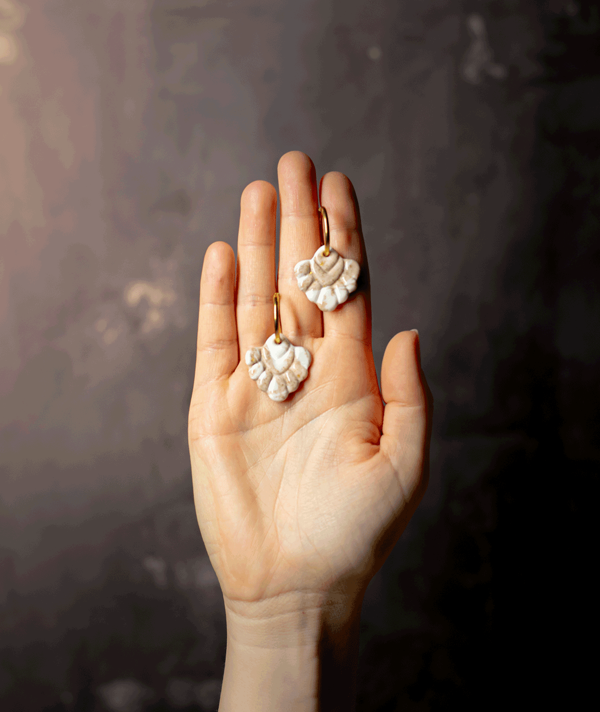 charm_20_a beige coral hoop earrings with ivory white and sandy beige polymer clay charms displayed on an open hand