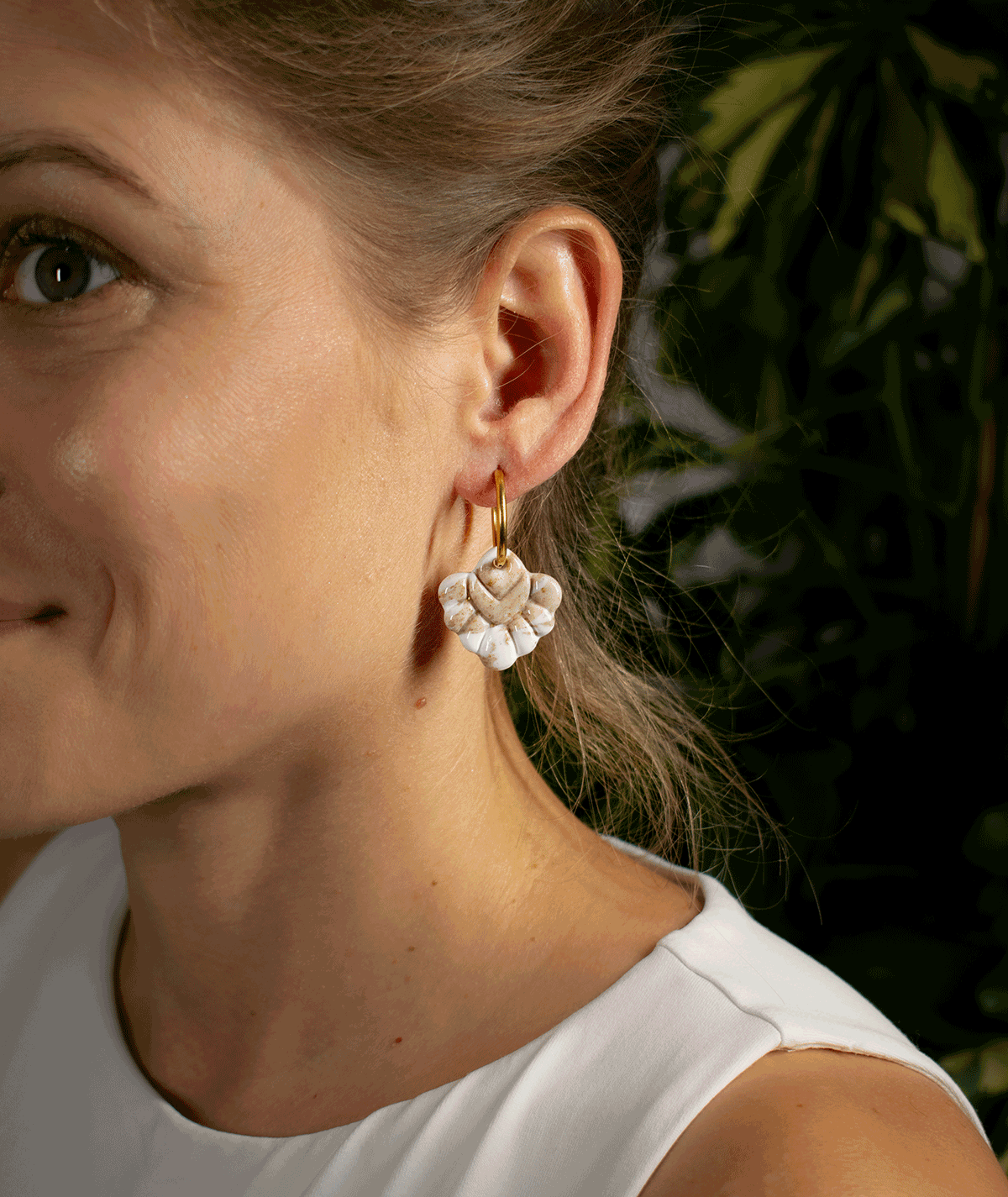 charm_20_b woman wearing beige coral hoop earrings with textured ivory and sand-coloured charms on gold-tone hoops