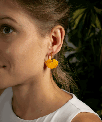 woman wearing yellow shell hoop earrings with golden yellow seashell charms and gold-tone hoops
