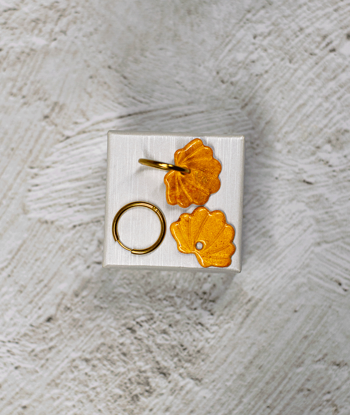 charm_21_c1 yellow shell hoop earrings with sculpted ridges and shimmering golden yellow polymer clay charms on a white display stand